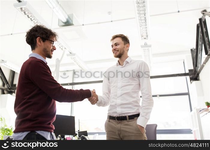 business, people, gesture, cooperation and partnership concept - happy businessmen making handshake at office