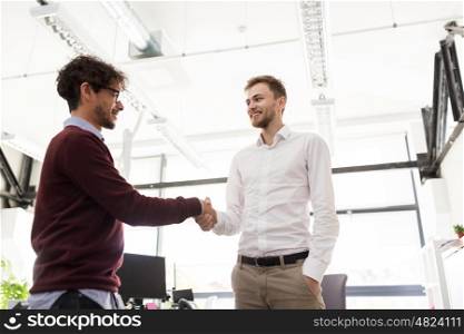 business, people, gesture, cooperation and partnership concept - happy businessmen making handshake at office