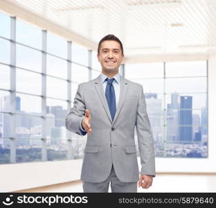 business people, gesture, partnership, real estate and greeting concept - happy smiling businessman in suit shaking hand over city office window background