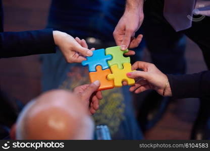 business people group assembling jigsaw puzzle and represent team support and help concept, top view perspective at modern bright office interior