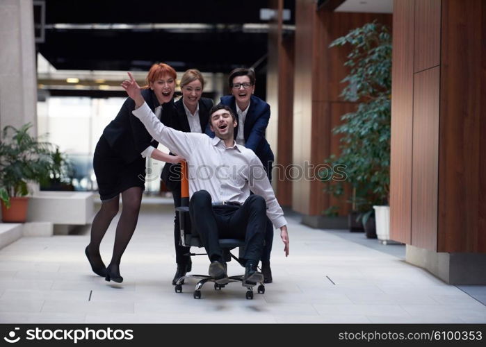 business people group at modern office indoors have fun and push office chair on corridor