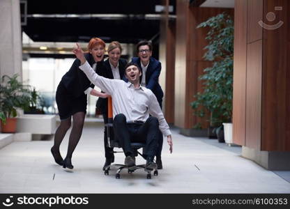 business people group at modern office indoors have fun and push office chair on corridor