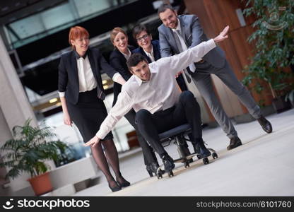 business people group at modern office indoors have fun and push office chair on corridor