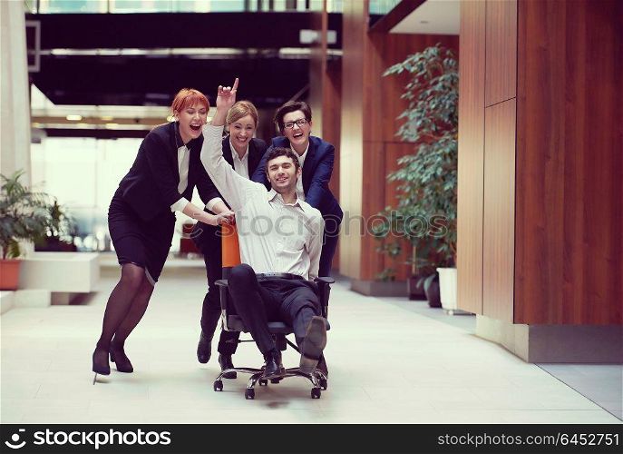 business people group at modern office indoors have fun and push office chair on corridor