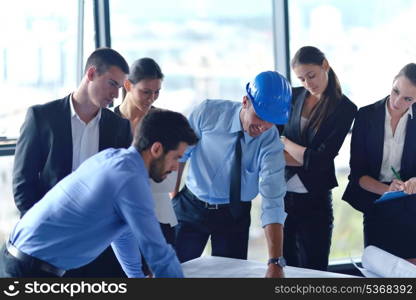 business people group on meeting and presentation in bright modern office with construction engineer architect and worker looking building model and blueprint plans