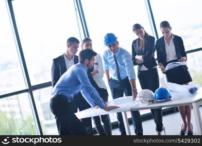 business people group on meeting and presentation in bright modern office with construction engineer architect and worker looking building model and blueprint planbleprint plans