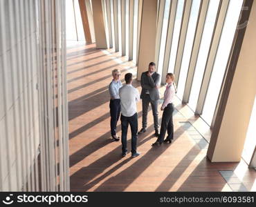 business people group standing together as team by window in modern bright office interior