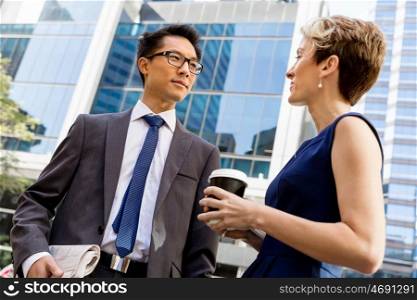 Business people having a talk while walking in a businesss district. Two colleagues walking together in a city