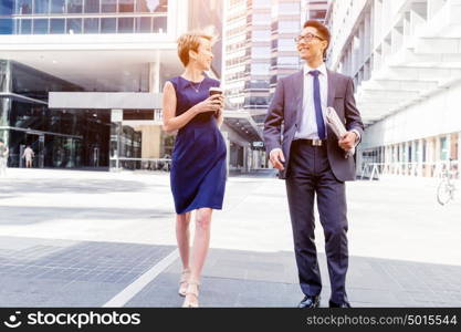 Business people having a talk while walking in a businesss district. Two colleagues walking together in a city