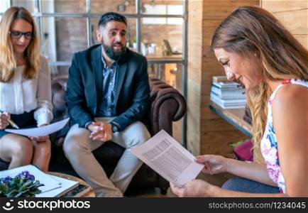 Business people having an informal work meeting sitting on the couch. Selective focus on woman in foreground. Businesspeople having an informal work meeting