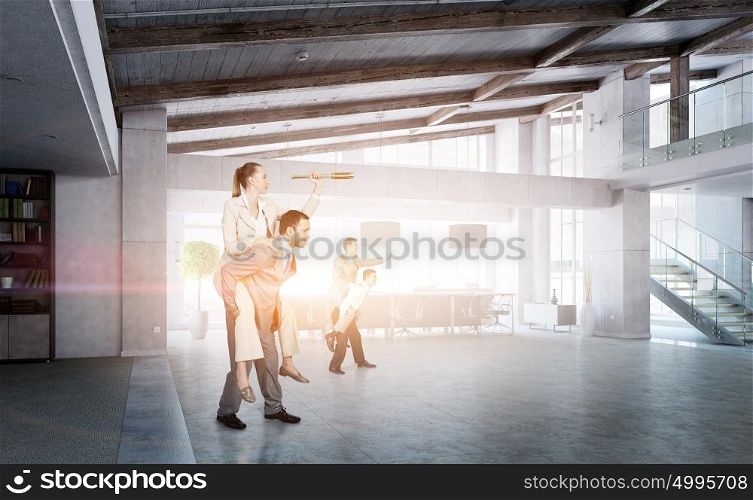 Business people having break in office. Businesswoman riding on back of her colleague in modern office