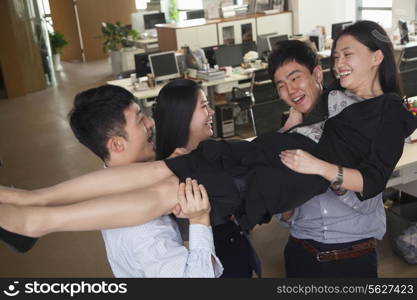 Business people having fun carrying coworker