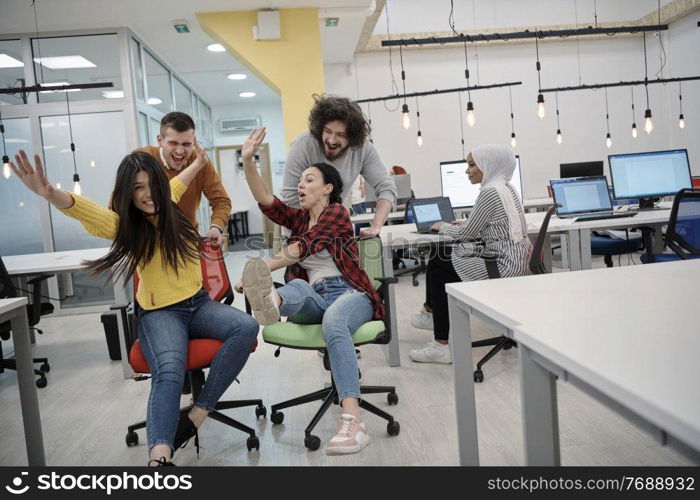 business people having fun while racing on office chairs