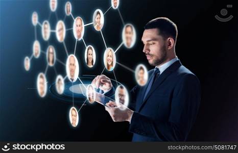 business, people, headhunting, communication and modern technology concept - businessman in suit working with transparent tablet pc computer and contacts network over black background. businessman with tablet pc and contacts network