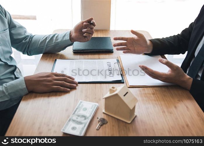 Business people home sales broker is using a pen pointing to the house model and describing the various components of the house.