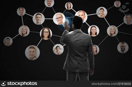 business, people, human resources, headhunting and technology concept - businessman working with network contacts icons from back over black background. businessman working with network contacts icons