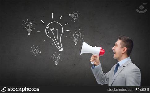 business, people, idea and announcement concept - happy businessman in suit speaking to megaphone and light bulbs over dark gray concrete wall background
