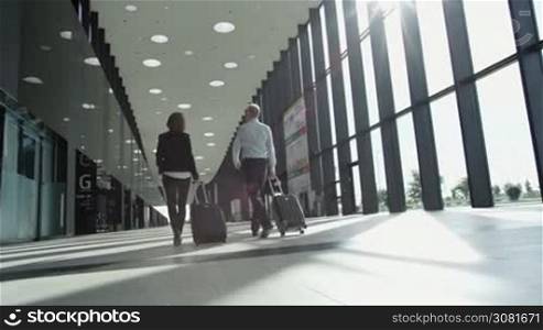 Business people in formal clothes walking in airport terminal with suitcases
