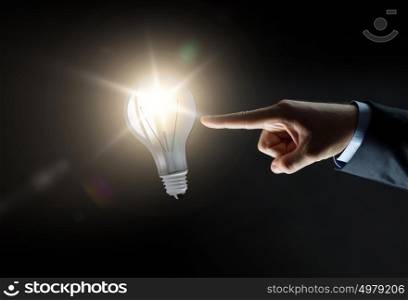business, people, inspiration and idea concept - close up of businessman hand pointing finger to over black background. businessman pointing finger to lightbulb over dark