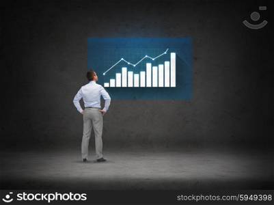business, people, inspiration and strategy concept - businessman looking at chart over concrete room background from back