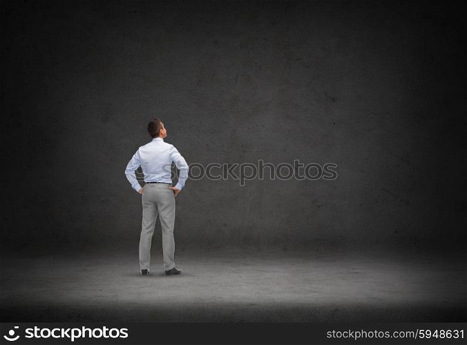 business, people, inspiration and strategy concept - businessman thinking over concrete room background from back
