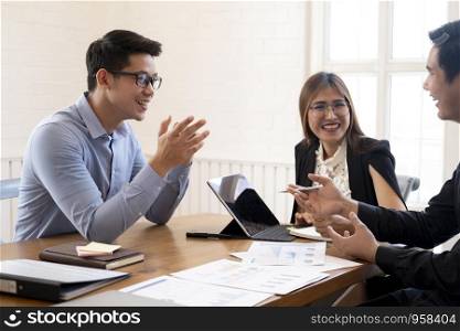 Business people laughing together while discussing paperwork during a meeting.