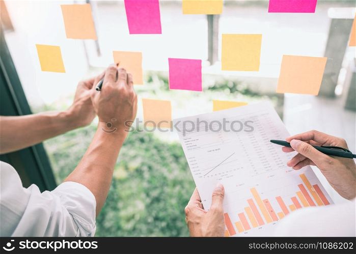 Business people meeting at office and use sticky notes on glass wall in office, diverse employees people group planning work together brainstorm strategy