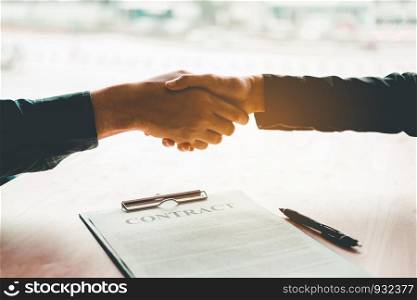 Business people negotiating a contract handshake between two colleagues