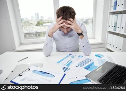 business, people, paperwork and deadline concept - stressed businessman with papers and charts sitting at table in office. stressed businessman with papers in office