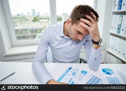 business, people, paperwork and deadline concept - stressed businessman with papers and charts sitting at table in office