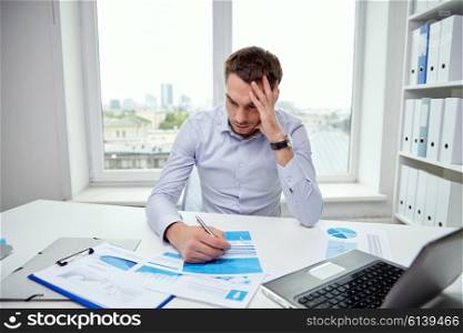 business, people, paperwork and deadline concept - stressed businessman with papers and charts sitting at table in office