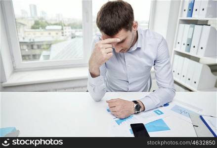 business, people, paperwork and deadline concept - stressed businessman with smartphone, papers and charts sitting at table in office. stressed businessman with papers in office