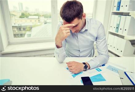 business, people, paperwork and deadline concept - stressed businessman with smartphone, papers and charts sitting at table in office