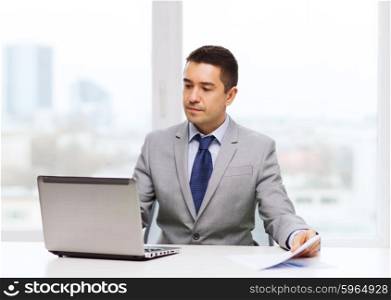 business, people, paperwork and technology concept - businessman with laptop computer and papers working in office