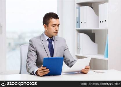 business, people, paperwork and technology concept - businessman with tablet pc and papers in office