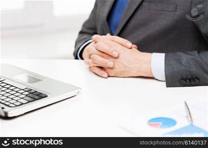 business, people, paperwork and technology concept - close up of businessman with laptop and papers in office