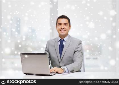 business, people, paperwork and technology concept - smiling businessman with laptop computer and papers working in office over snow effect