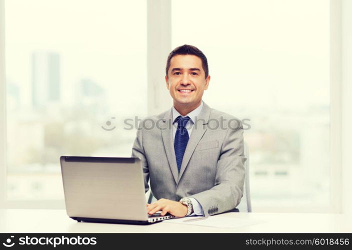 business, people, paperwork and technology concept - smiling businessman with laptop computer and papers working in office