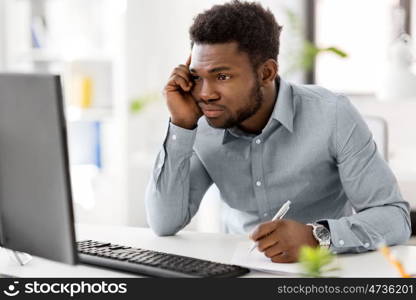 business, people, paperwork and technology concept - stressed african american businessman with computer and papers working at office. businessman with computer and papers at office. businessman with computer and papers at office