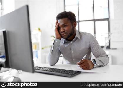 business, people, paperwork and technology concept - stressed african american businessman with computer and papers working at office. businessman with computer and papers at office. businessman with computer and papers at office