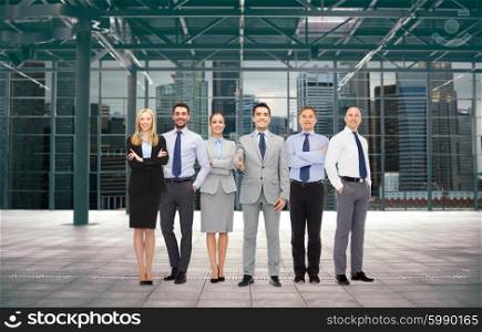 business, people, partnership and cooperation concept - group of smiling businesspeople over empty urban city construction background