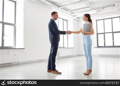 business people, partnership and cooperation concept - happy smiling businesswoman with folder and businessman shake hands at office. businesswoman and businessman shake hands