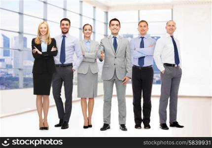 business, people, partnership and gesture concept - group of smiling businessmen making handshake over office room background
