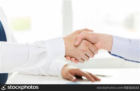 business, people, partnership, gesture and cooperation concept - close up of hands making handshake in office