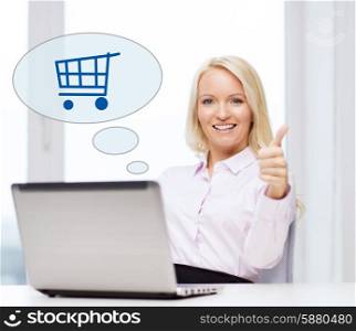 business, people, sale, gesture and technology concept - smiling businesswoman or student showing thumbs up with laptop computer and shopping trolley in text bubble at office