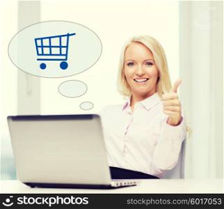 business, people, sale, gesture and technology concept - smiling businesswoman or student showing thumbs up with laptop computer and shopping trolley in text bubble at office