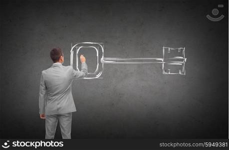business, people, security and solution concept - businessman drawing key from back over dark gray concrete wall background