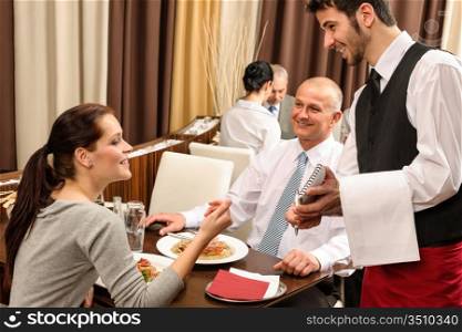 Business people served by waiter enjoy lunch at the restaurant