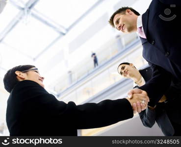 Business people shaking hands in the entrance hall of the office building. Selective focus is placed on the hands.