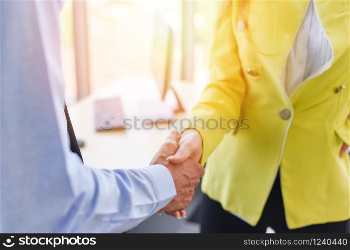 Business people shaking hands standing with colleagues after meeting or negotiation business man and business woman teamwork partnership and handshake success. Man and woman are shaking hand in office